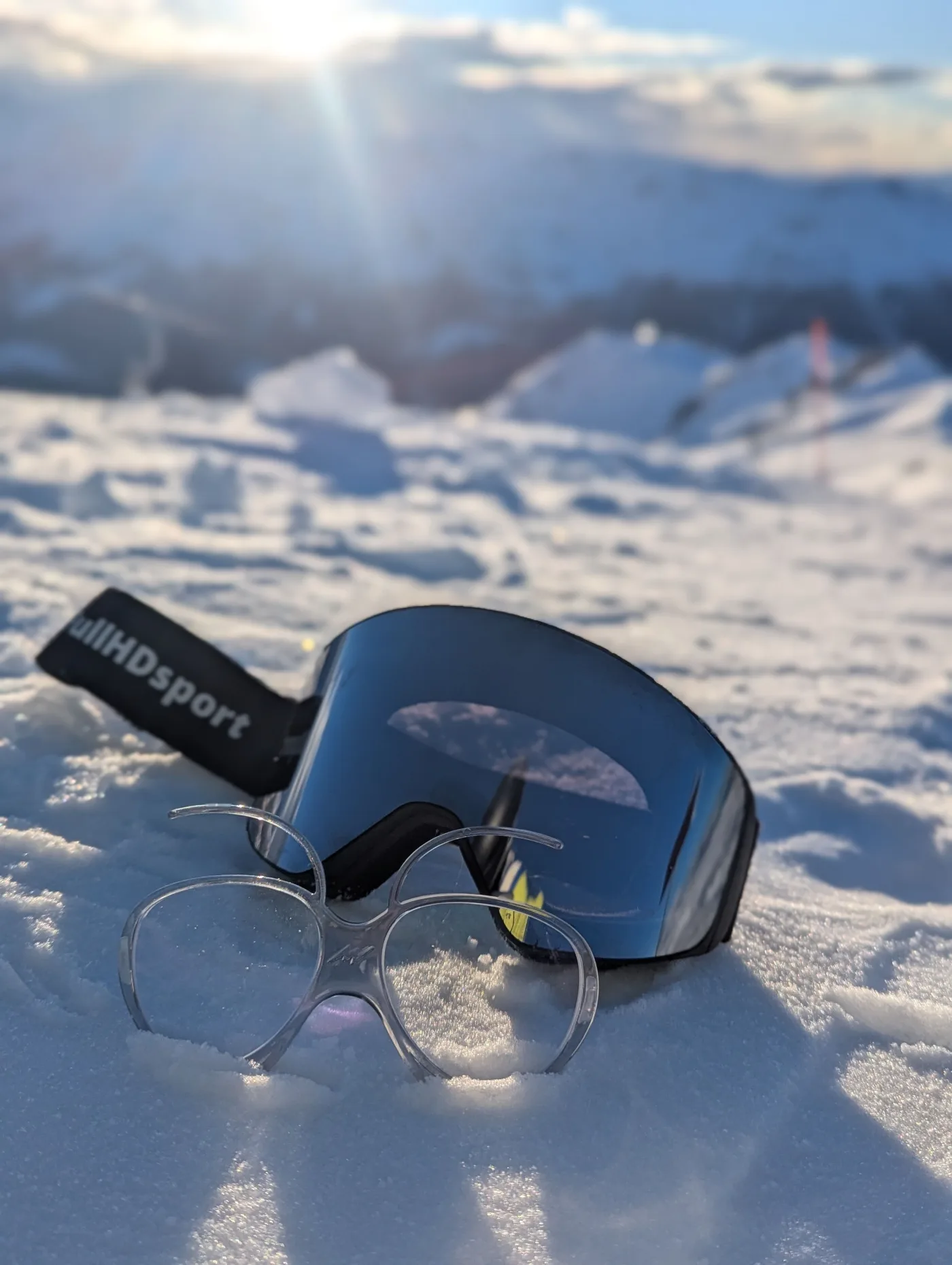 Un UniClip posé dans la neige devant un masque FullHDsport, au soleil